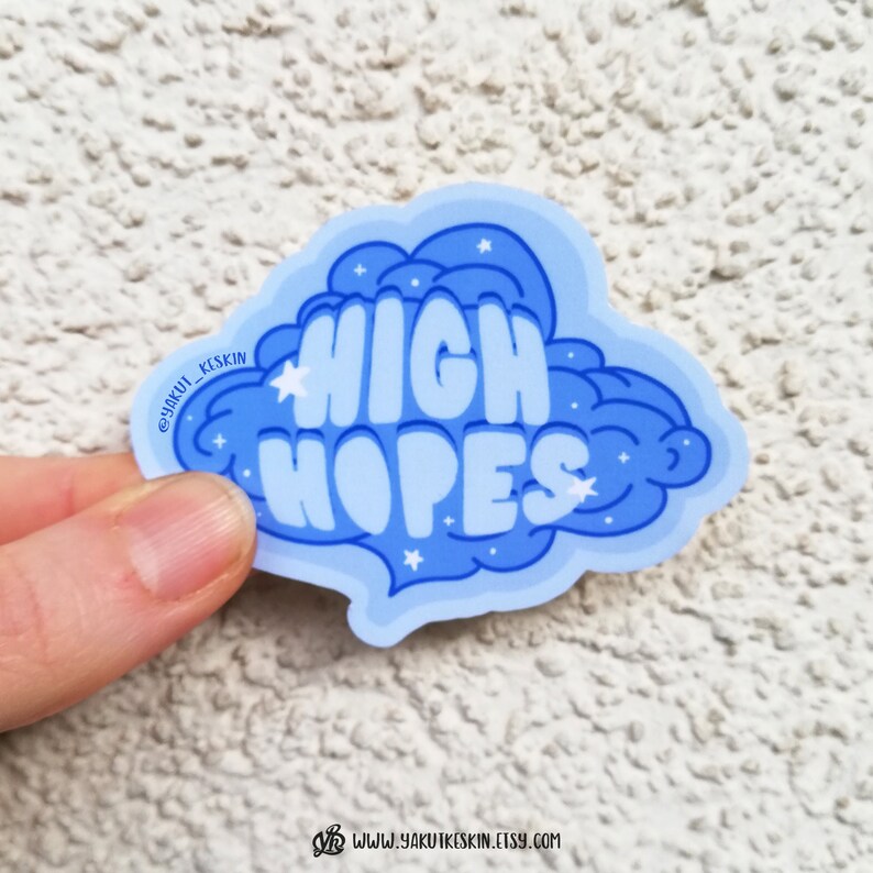 Puede incluir: Pegatina azul y blanca en forma de nube con el texto "HIGH HOPES". La pegatina tiene un dise&ntilde;o brillante.