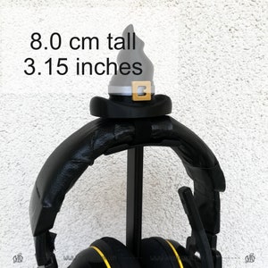 May include: Black headphones with a black and silver witch hat on top of the stand. The hat is 8.0 cm tall or 3.15 inches tall.
