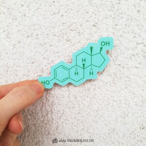 May include: A light blue sticker with a chemical formula for estradiol, a type of estrogen. The formula is printed in green text.