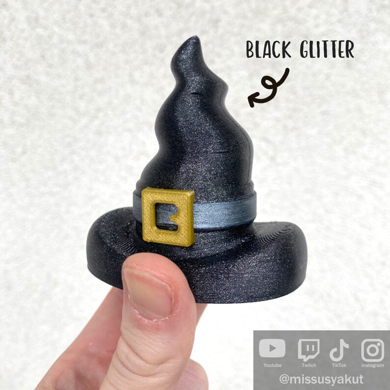May include: Black glitter witch hat with a gold buckle and a silver band. The hat is 3D printed and has a pointed top.