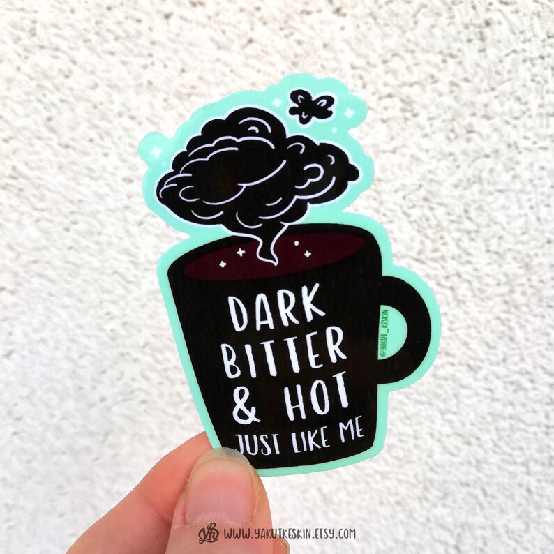 May include: A sticker of a black coffee mug with steam coming out of it. The mug has the text "DARK BITTER & HOT JUST LIKE ME" on it. There is a small butterfly above the mug.