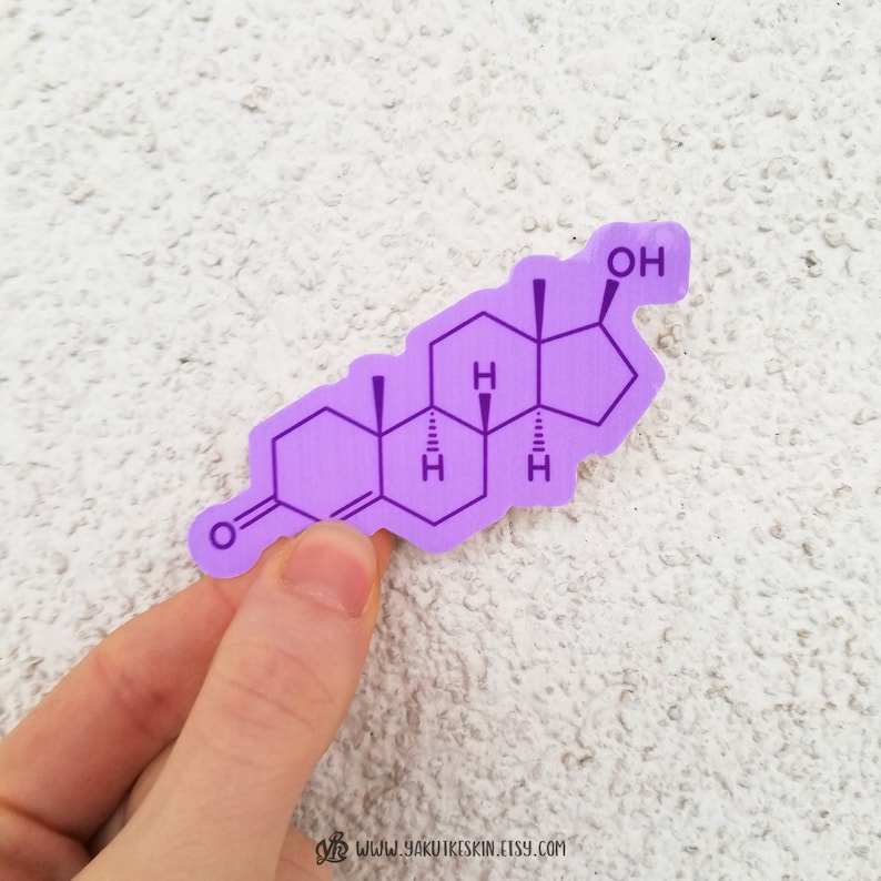 May include: A purple sticker featuring a detailed illustration of a chemical structure, likely a hormone. The sticker has a clean, modern design with the chemical formula clearly visible. The sticker is held by a hand against a textured white background.