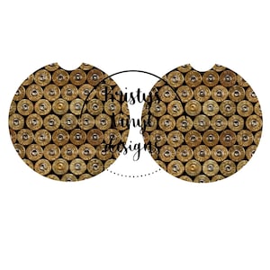 Może przedstawiać: Dwa okrągłe podkładki pod kubki z wzorem złotych łusek pocisków. Podkładki są zaprojektowane do dopasowania do standardowych kubków na napoje.