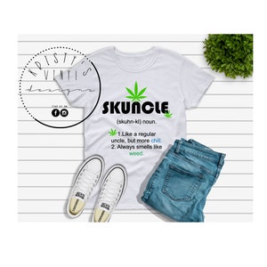 Pode incluir: Camiseta branca com um design de folha de maconha verde e a palavra "SKUNCLE" escrita em preto. O texto abaixo define a palavra como um "tio normal, mas mais relaxado" e "sempre cheira a erva".