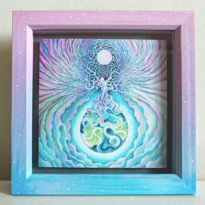 May include: A square framed artwork featuring a central figure with flowing lines extending upwards towards a white circle and downwards into a swirling blue and green sphere. The frame has a gradient finish transitioning from pink to blue with white speckles.