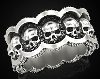 May include: A silver ring featuring a repeating pattern of five skull designs. The ring is crafted from textured metal and has a slightly rounded shape.