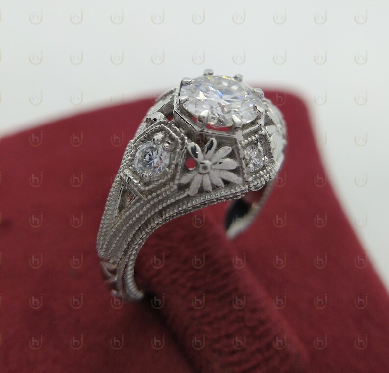 May include: A silver ring with a large, round, clear gemstone surrounded by smaller gemstones and intricate floral designs.