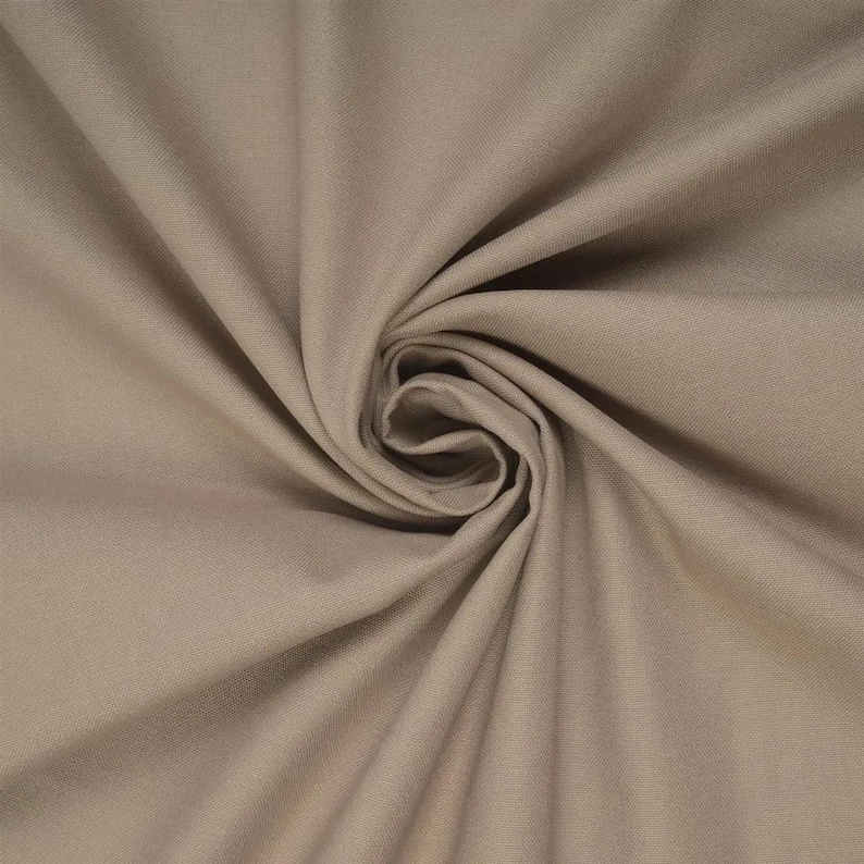 May include: A solid light brown fabric with a smooth, matte texture. The material is gathered in the centre, creating a series of radiating folds and soft shadows that highlight the consistent, neutral tone and the fine weave of the textile.