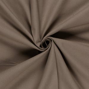 May include: A solid taupe-coloured fabric featuring a dense, woven texture. The material is gathered in the centre, creating deep, radiating folds and shadows that highlight the smooth, matte surface and the consistent earthy brown tone throughout.