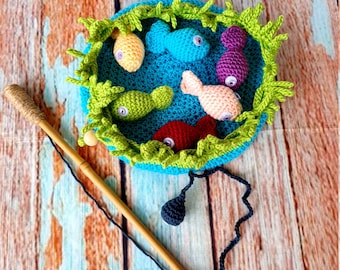 May include: A crocheted fishing game with a blue pond, green lily pads, and six colorful fish. A wooden fishing rod with a black string and a dark blue bobber is included.