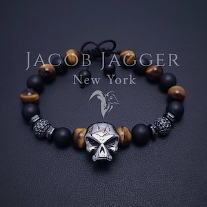Bracciale da uomo con teschio in acciaio inossidabile con occhio di tigre e onice nero opaco. Lunghezza regolabile con perline naturali da 8 mm e ciondoli in acciaio argentato.
