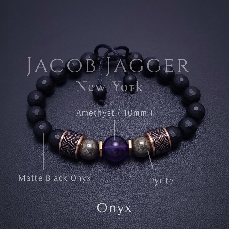 May include: Black onyx gemstone bracelet with gold accents and a purple amethyst gemstone. The bracelet is made by Jacob Jagger New York.
