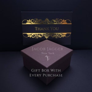 May include: A brown gift box with gold lettering that reads "Jacob Jagger New York" and "Gift Box With Every Purchase". The box is sitting on a black surface. A separate card with gold lettering that reads "Thank You" is sitting on top of the box.