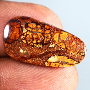 Peut inclure: Un cabochon d'opale en forme de larme avec un motif brun, orange et blanc. L'opale a une qualité chatoyante et irisée.