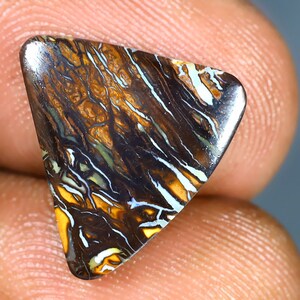 May include: A triangular, dark brown opal gemstone with white and gold veins. The opal has a smooth, polished surface.