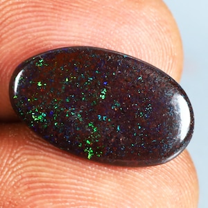 May include: A dark brown oval opal gemstone with green and blue flashes of color.