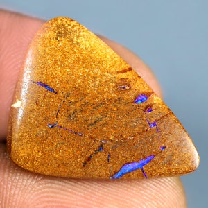 Könnte beinhalten: Ein dreieckiges Stück Opal mit brauner Basis und schillernden blauen und violetten Blitzen.