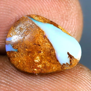 May include: A teardrop-shaped opal gemstone with a brown matrix and a blue and white iridescent flash.