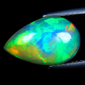 May include: A teardrop-shaped opal gemstone with a green, blue, and orange iridescent sheen.