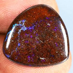 May include: A brown and purple opal gemstone with a teardrop shape. The opal has a rough, textured surface and a high polish.