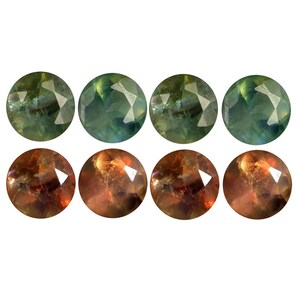 May include: Eight round, faceted gemstones. The top row shows four green and blue gems, and the bottom row has four gems with orange and brown tones. Each gem has a polished, reflective surface.