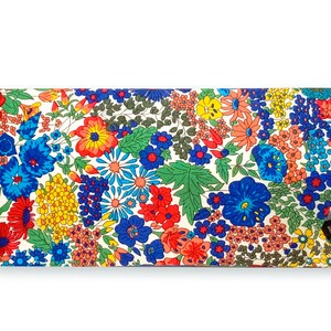 May include: A floral patterned glasses case with a white background and a variety of colorful flowers, including red, blue, yellow, and orange. A pair of glasses is partially visible in the case.