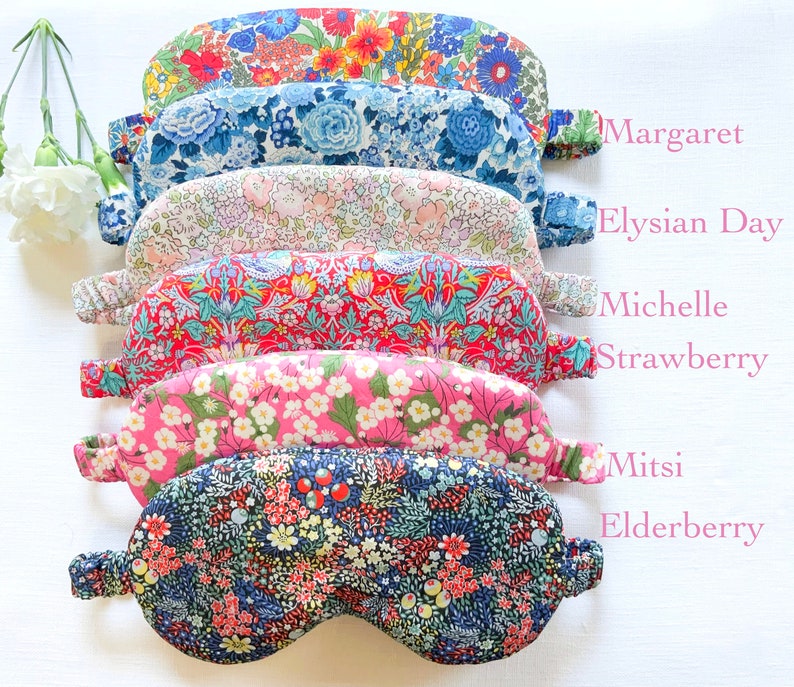 May include: A stack of six colorful floral eye masks with different patterns. The eye masks are labeled with names: Margaret, Elysian Day, Michelle Strawberry, Mitsi Elderberry.