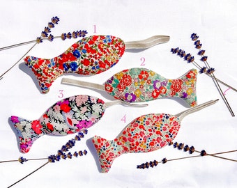 May include: Four colorful fish-shaped fabric toys with floral patterns. Each toy has a white ribbon attached to it.