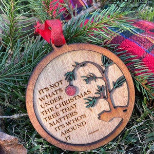 May include: A wooden Christmas ornament with a quote from the movie "A Charlie Brown Christmas" that reads "It's not what's under the Christmas tree that matters, it's who's around it."