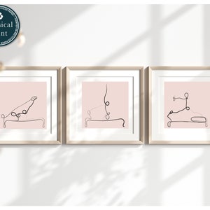 Op de afbeelding: Drie ingelijste prints met een roze achtergrond en zwarte lijntekeningen van mensen die yogaposes doen op een reformer.