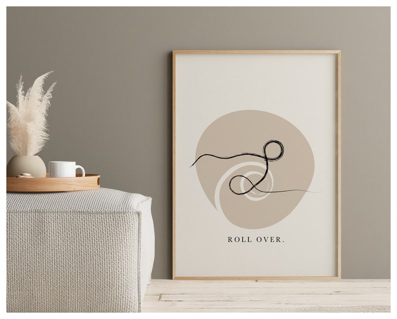 Puede incluir: Una impresi&oacute;n de arte minimalista con un dibujo de l&iacute;nea negra de un remolino sobre un fondo beige. El texto "ROLL OVER." est&aacute; impreso debajo del dibujo.