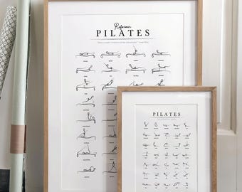 May include: Two framed Pilates exercise charts with a light wood frame. The larger chart is labeled "Reformer Pilates" and the smaller chart is labeled "Pilates". Both charts feature black line drawings of Pilates poses.