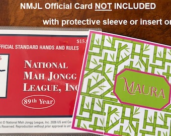May include: A protective sleeve containing a red National Mah Jongg League 2026 official standard hands and rules card, alongside a white insert featuring a green bamboo pattern and a central pink-bordered hexagon with the name Maura printed.