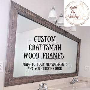 May include: A large rectangular mirror with a dark brown, craftsman-style wooden frame. The text "CUSTOM CRAFTSMAN WOOD FRAMES" is displayed on the mirror, along with "MADE TO YOUR MEASUREMENTS AND YOU CHOOSE COLOR!"