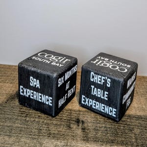 May include: Two black wooden cubes with white text. One cube reads "Cogir South Bay, Spa Experience, Six Months at Half Rent." The other cube reads "Cogir South Bay, Chef's Table Experience."