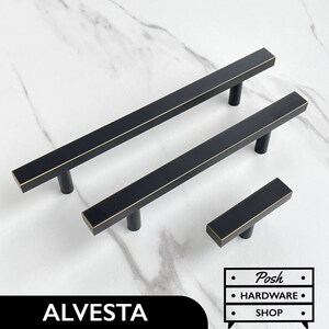 May include: Three black cabinet pulls with a gold trim. The pulls are rectangular in shape and have a simple design. The smallest pull is 7.6 cm long, the middle pull is 15.2 cm long, and the largest pull is 22.9 cm long.
