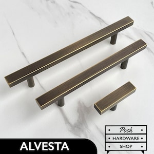 May include: Three brushed brass cabinet pulls in different sizes. The pulls have a rectangular shape with rounded edges and a brushed finish.