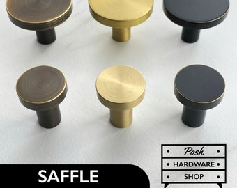 May include: Six cabinet knobs in three different finishes: antique brass, polished brass, and black. The knobs are round with a flat top and a short, cylindrical base.