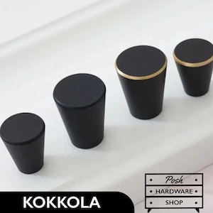 May include: Four black cabinet knobs with a gold trim. The knobs are different sizes and are arranged in a row from smallest to largest.