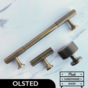 May include: Set of four antique brass cabinet knobs and pulls with a ribbed design. The knobs and pulls are in various sizes.  The largest pull is 15 cm long.  The smaller pulls are 7.5 cm long.  The knobs are 2.5 cm in diameter.  The knobs and pulls are all made of metal and have a brushed finish.  The knobs and pulls are perfect for adding a touch of vintage style to any home.