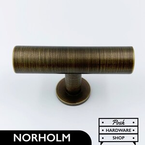 Könnte beinhalten: Ein T-förmiger Schrankgriff aus gebürstetem Antikmessing mit runder Basis.