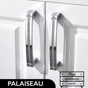 Peut inclure: Deux poignées de porte de placard argentées avec un design en cristal. Les poignées sont montées sur une porte de placard blanche. Le texte "PALAISEAU" est visible en bas de l'image. Le texte "Posh Hardware Shop" est visible en bas à droite de l'image.