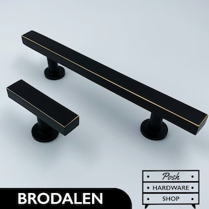 Può includere: Due maniglie per armadietti nere con finitura dorata. La maniglia più grande è lunga 15 cm e la più piccola 7,5 cm. Brodalen.