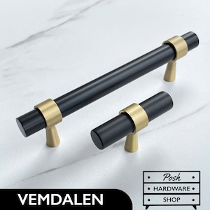 May include: Two black cabinet pulls with gold accents. The larger pull is 12.7 cm long and the smaller pull is 7.6 cm long. The pulls have a modern, minimalist design.