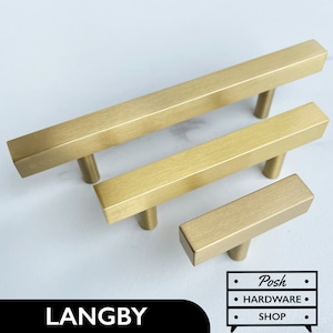 Könnte beinhalten: Drei Schrankgriffe aus gebürstetem Messing in verschiedenen Größen. Die rechteckigen Griffe haben ein T-Bar-Design und sind auf einer weißen Oberfläche angeordnet. Das Wort "LANGBY" ist unten links in Schwarz gedruckt. Das Logo "Posh Hardware Shop" befindet sich unten rechts.
