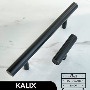 Könnte beinhalten: Zwei schwarze Metall-Schrankgriffe mit abgerundeten Enden. Der größere Griff ist 15 cm lang und der kleinere Griff ist 7,5 cm lang. Die Griffe haben eine gebürstete Oberfläche.