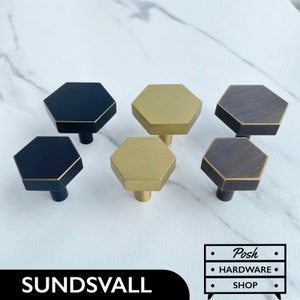 Peut inclure: Six boutons de cabinet hexagonaux en trois finitions différentes : noir, or et bronze. Les boutons ont un bord légèrement surélevé autour du périmètre.