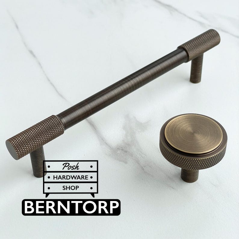 May include: A dark bronze cabinet handle with a knurled texture on the ends and a matching round cabinet knob with a knurled edge and a smooth center. The image includes a logo with the text Posh HARDWARE SHOP and BERNTORP.