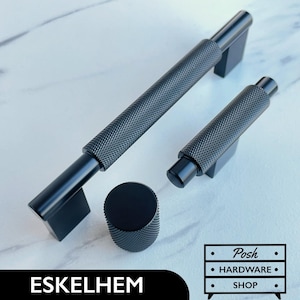 Peut inclure: Trois boutons et poignées de meuble en métal noir avec un design texturé et strié. Les boutons et les poignées sont de différentes tailles. Le texte "Posh Hardware Shop" est visible sur l'image.