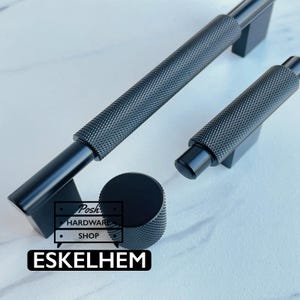 May include: Two matte black cabinet pulls and one matching round cabinet knob, all featuring a textured knurled surface. The hardware includes a logo graphic with the text Posh Hardware Shop and the word ESKELHEM printed in white on a black background.